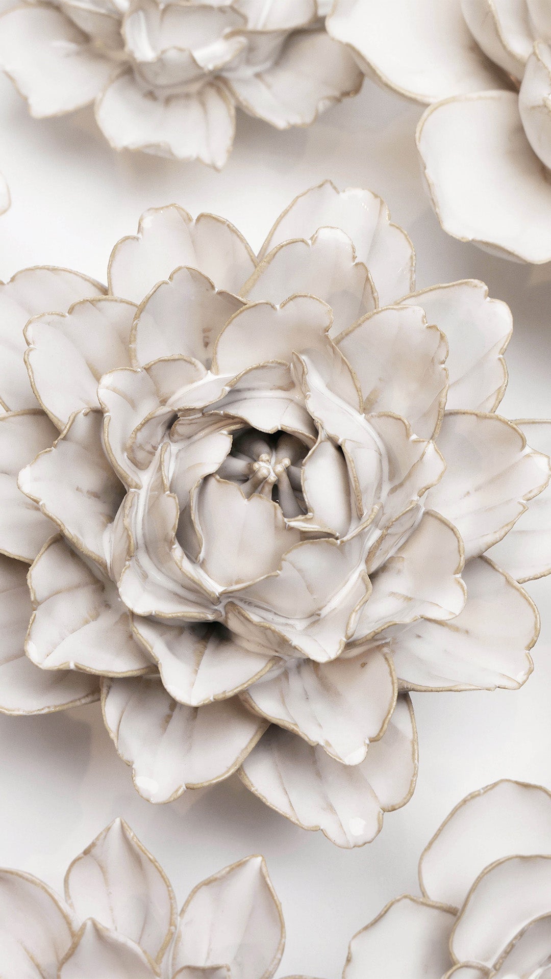 Ivory Comanche Peony on a white wall surrounded by other ivory ceramic flowers