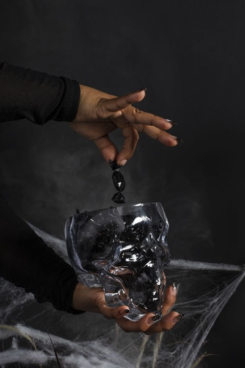 Glass mold of skull with black crystals and cobwebs.