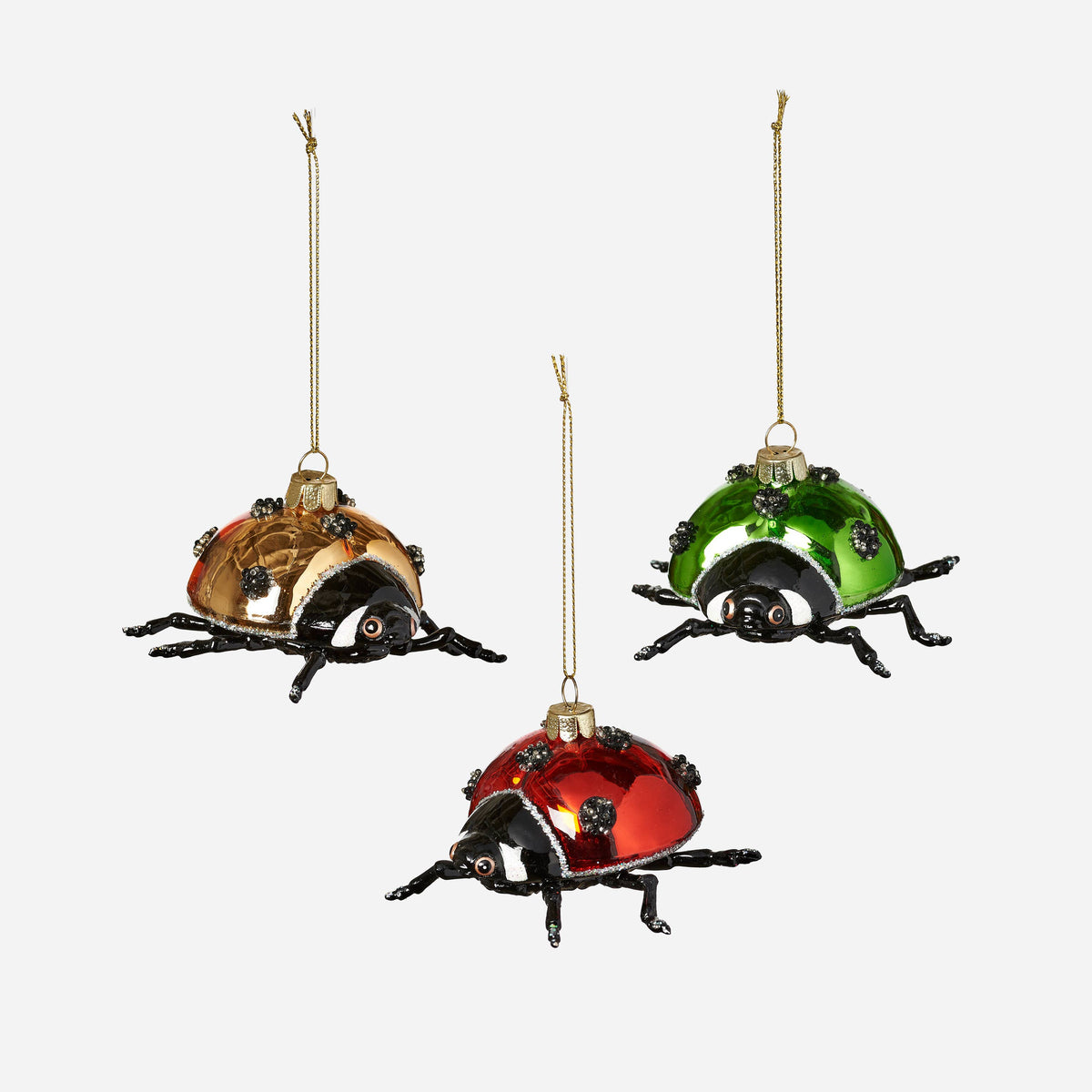 Three glass ladybug ornaments in gold, green, and red with black legs and gold hanging strings