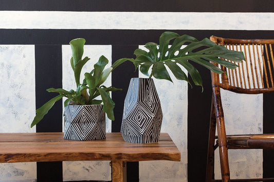 Abstract vase with linear designs in black and white with a plant.
