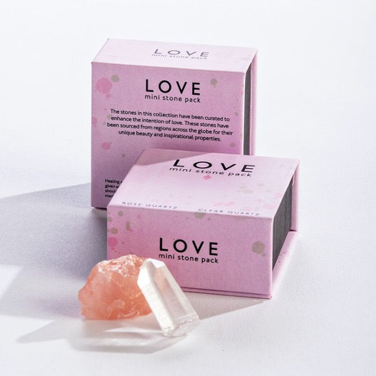 Pink box with 1 clear quartz stone and 1 rose quartz stone.