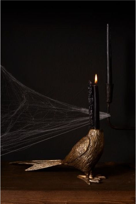 Pheasant taper holder, no head, in antique brass with black melting candle. cob web in background.