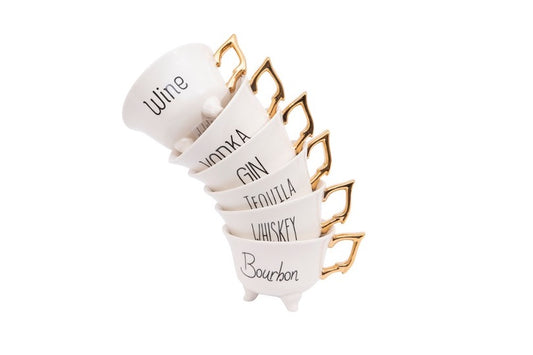 Six tea cups with gold handles stacked. Each tea cup has black text with Wine, Vodka, Gin, Tequila, Whiskey, or Bourbon on side.