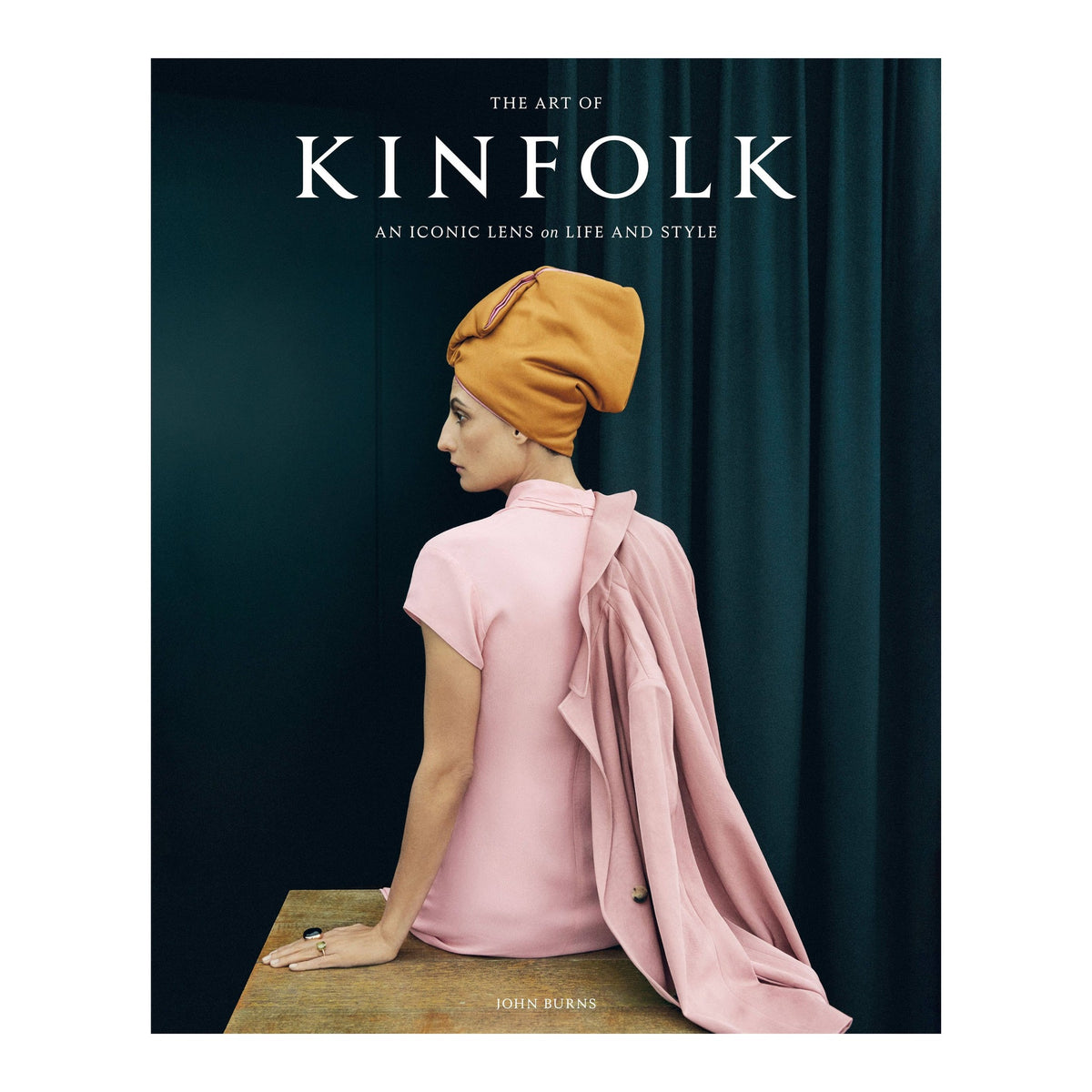 The Art of Kinfolk by John Burns, cover of a woman from behind in a pink dress and mustard headwrap