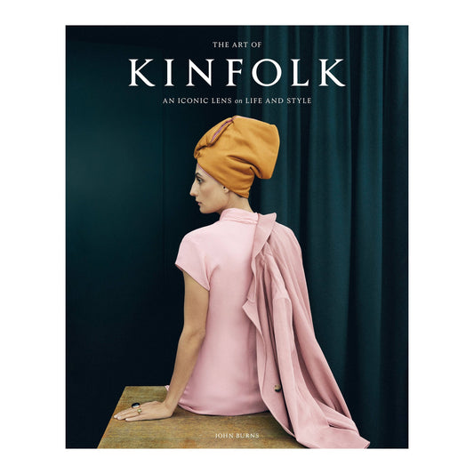 The Art of Kinfolk by John Burns, cover of a woman from behind in a pink dress and mustard headwrap