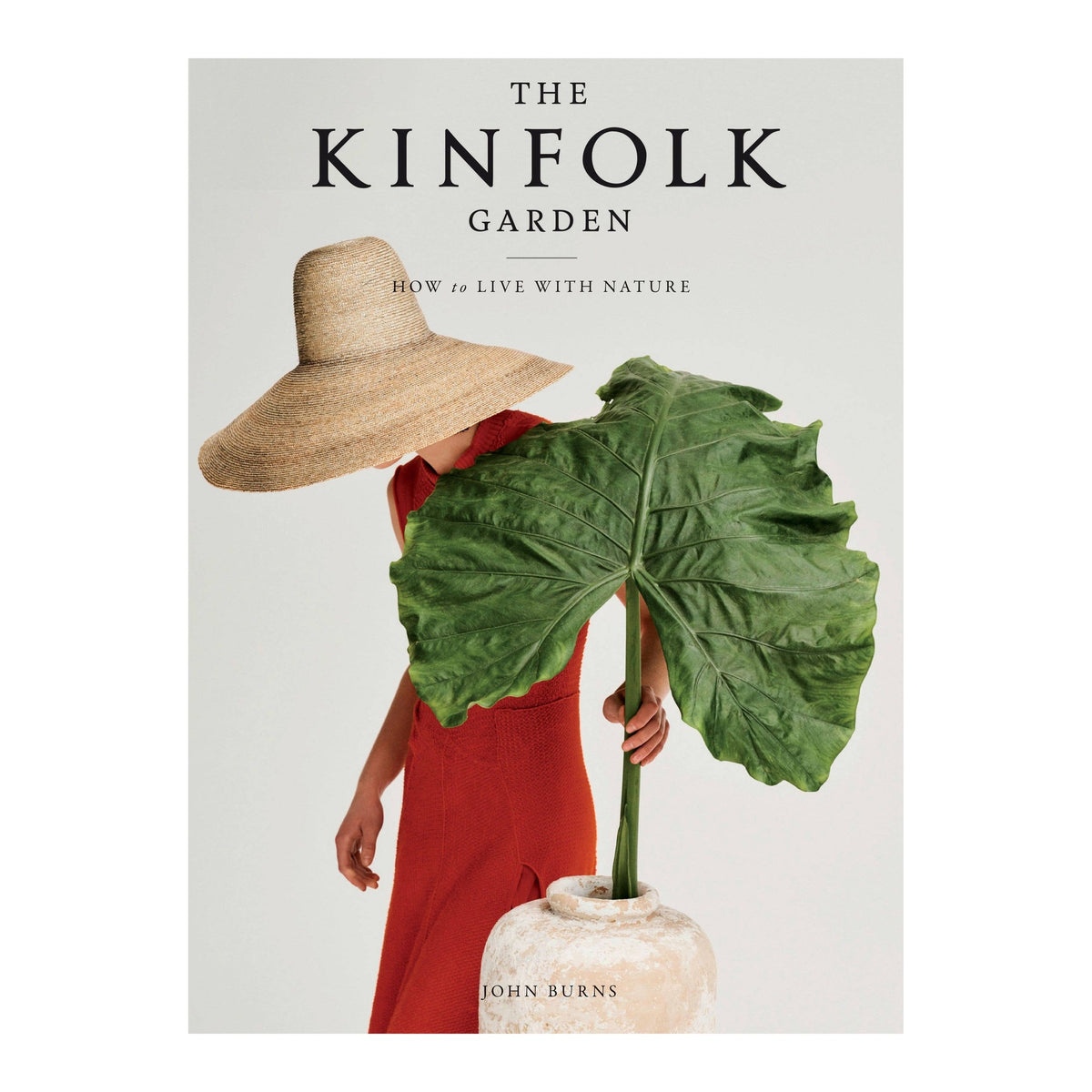 The Kinfolk Garden by John Burns, cover of a woman in a straw hat holding a large leaf