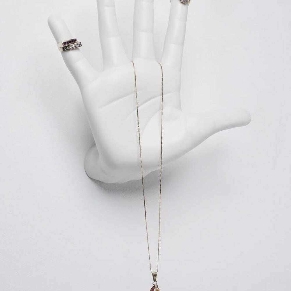 White ceramic talk to the hand wall mount close up, holding stacked rings and a long gold necklace