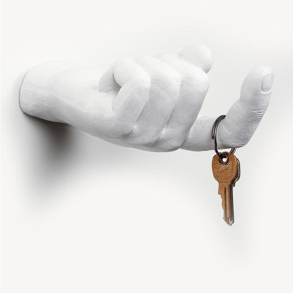 White hand-shaped wall hook with a beckoning finger holding a ring of brass keys, square view