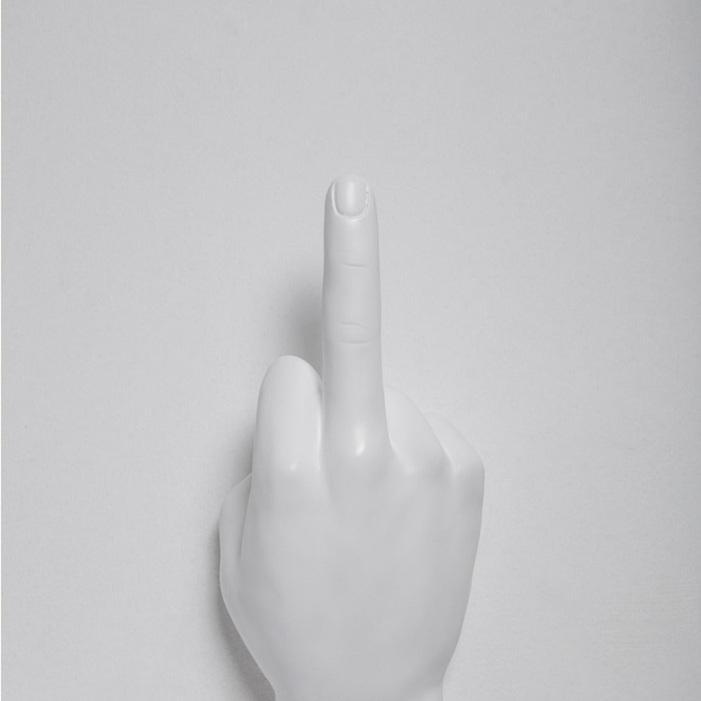 White middle finger hand wall hook mounted on a light gray wall, cropped close