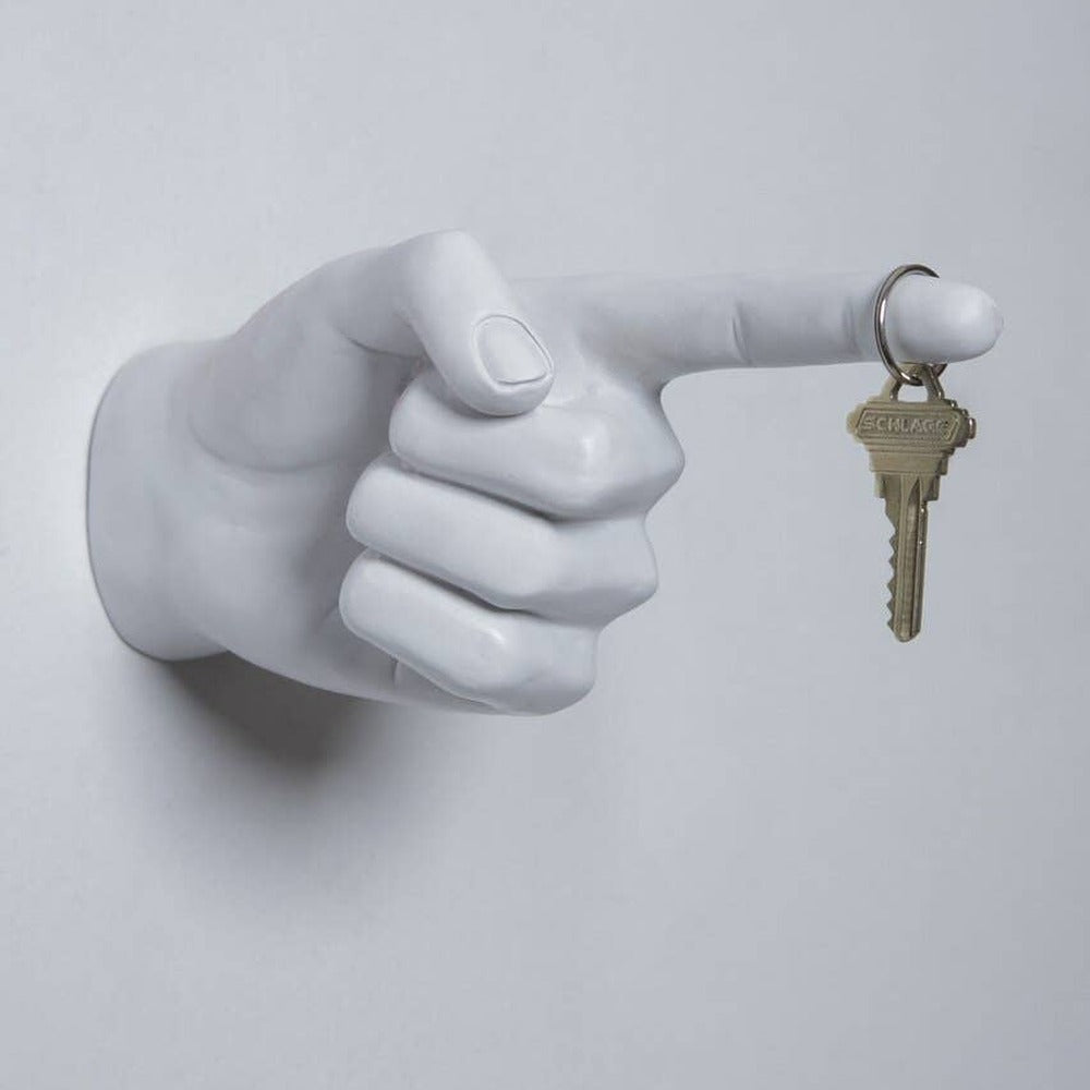 White pointing hand wall hook on a gray wall with a single house key hanging from the finger