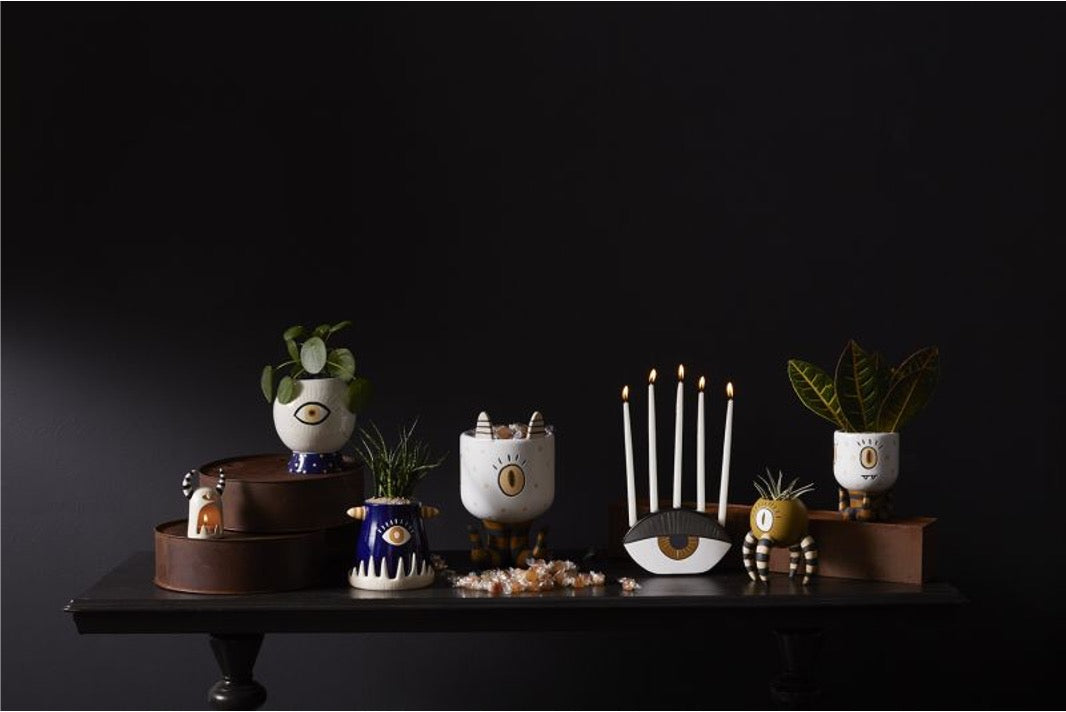 Collection of pots and candleholders with one eye illustration.