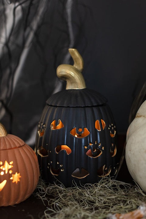 Black ceramic pumpkins with eye cutouts and gold handle.