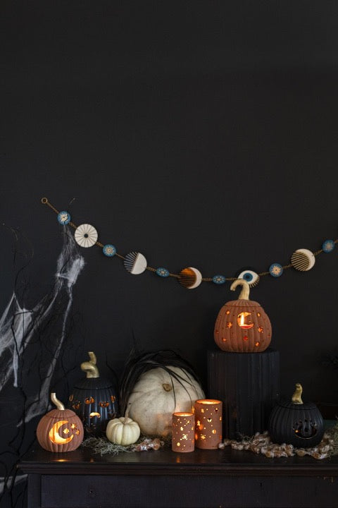 Ceramic votive and pumpkins with cutout moon and stars.