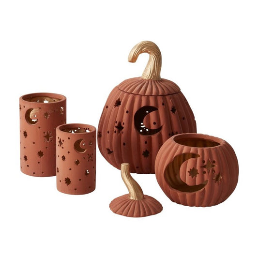 Ceramic votive and pumpkins with cutout moon and stars.