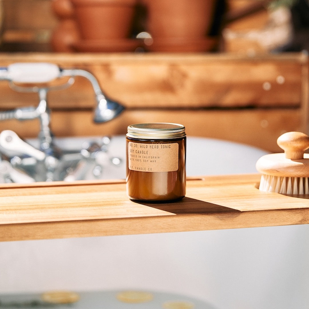 No. 36 Wild Herb Tonic Soy candle in amber jar with craft label and brass lid. Placed on kitchen counter. 