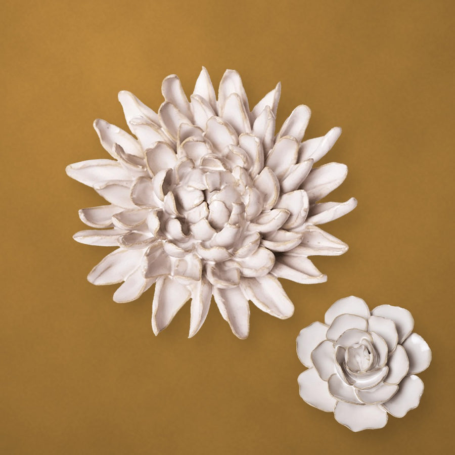 Ivory ceramic chrysanthemum and a small ranunculus on a mustard-gold plaster wall