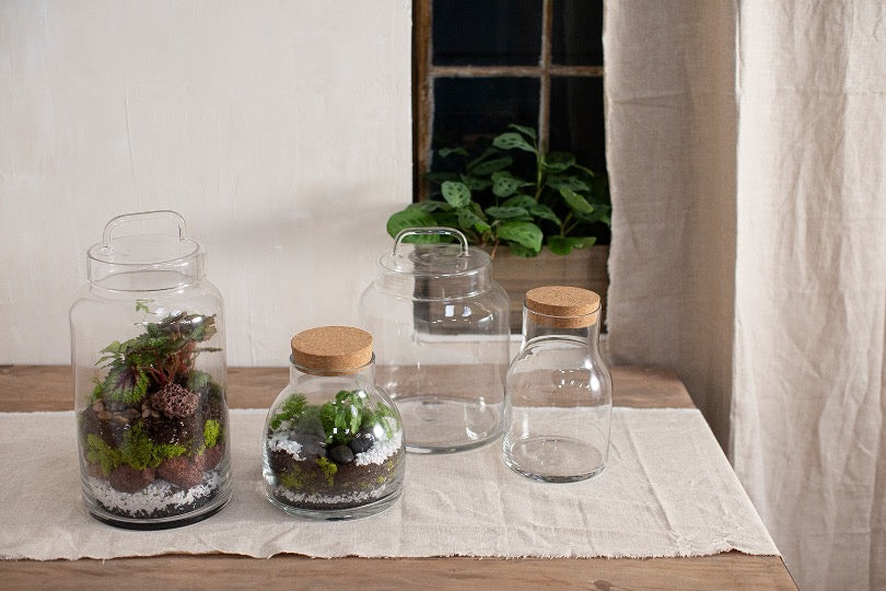 Set of glass terrariums on wooden table with linen runner