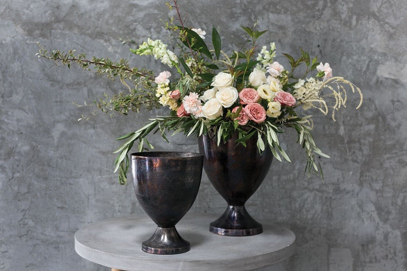 set of dark metal with pink, white rose floral arrangement with gray background.