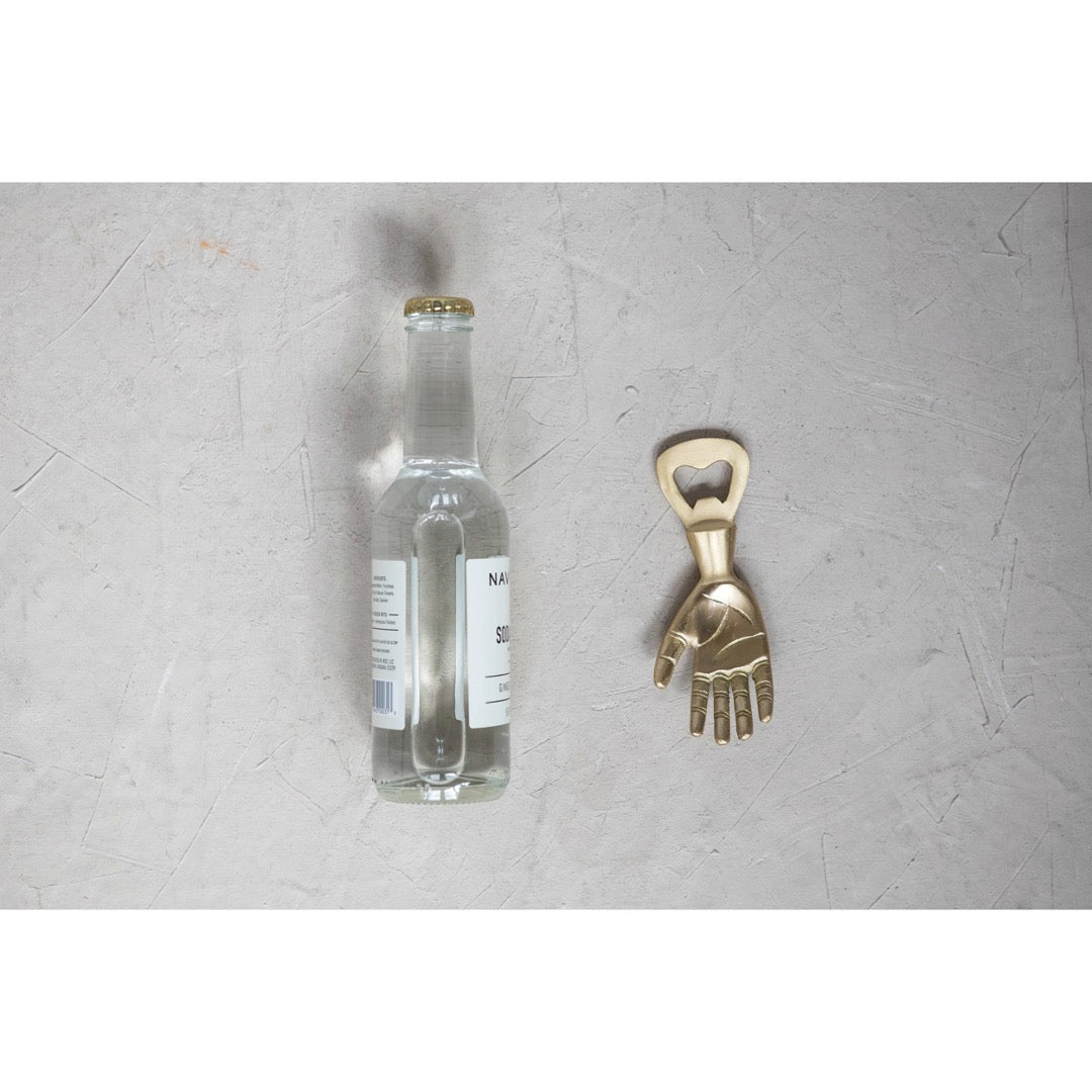 Brass hand bottle opener next to bottle