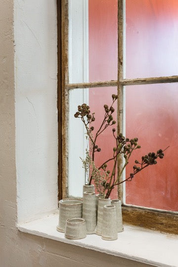 Multiple cylindrical vase in beige on window ledge with dried florals