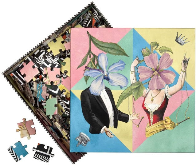 Christian Lacroix puzzle, whimsical illustrated art depicting male & female figures with floral faces. Pastel colored triangles in background. Pieces of puzzle in background.