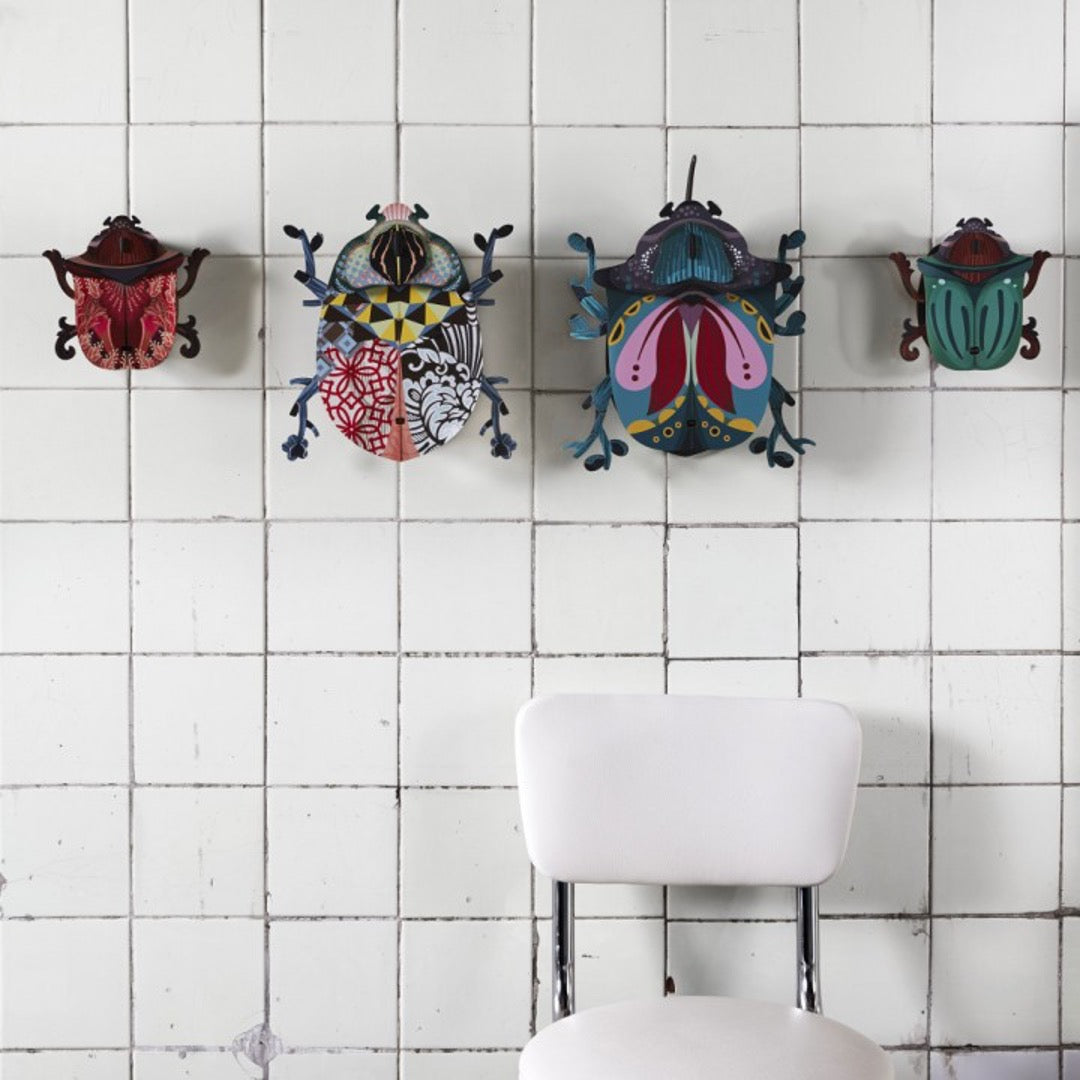 Collection of medium and large beetle wall cabinets on white tiled wall with white chair underneath