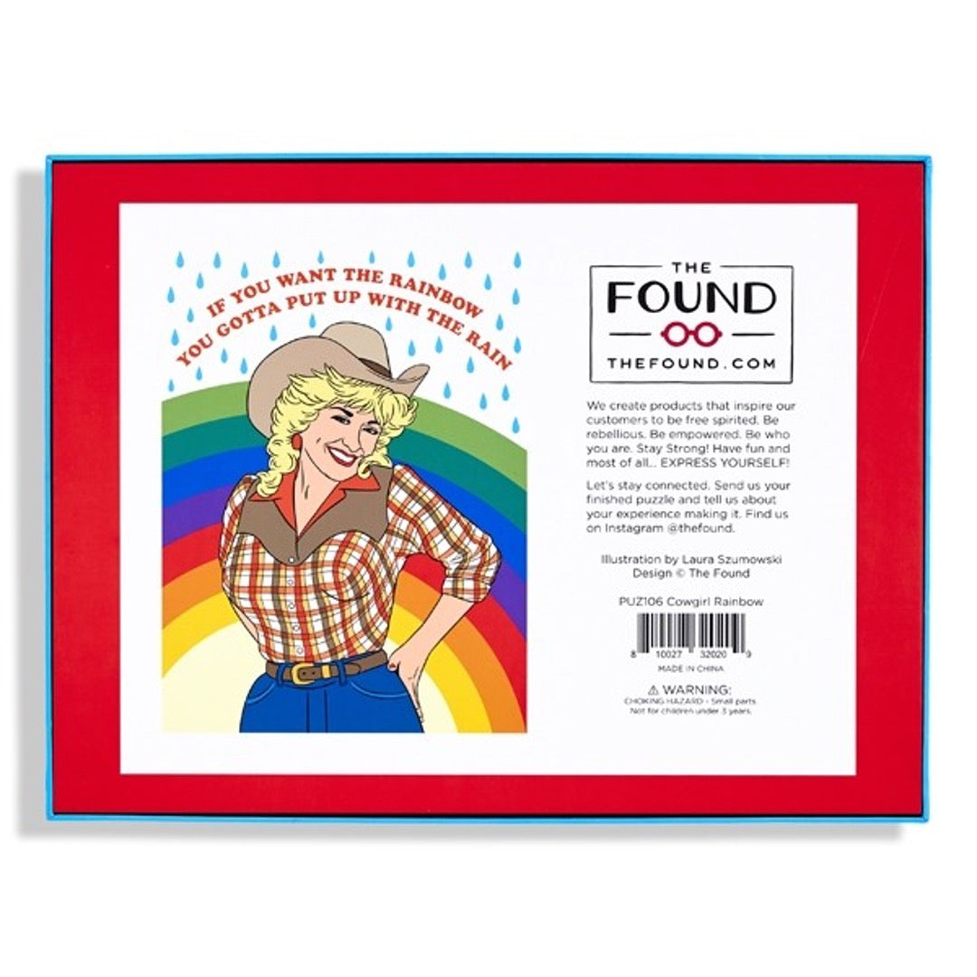 Dolly Parton puzzle in cowgirl outfit with rainbow and raindrops in background and text above in red that reads "If you want the rainbow, you gotta put up with the rain" back of box