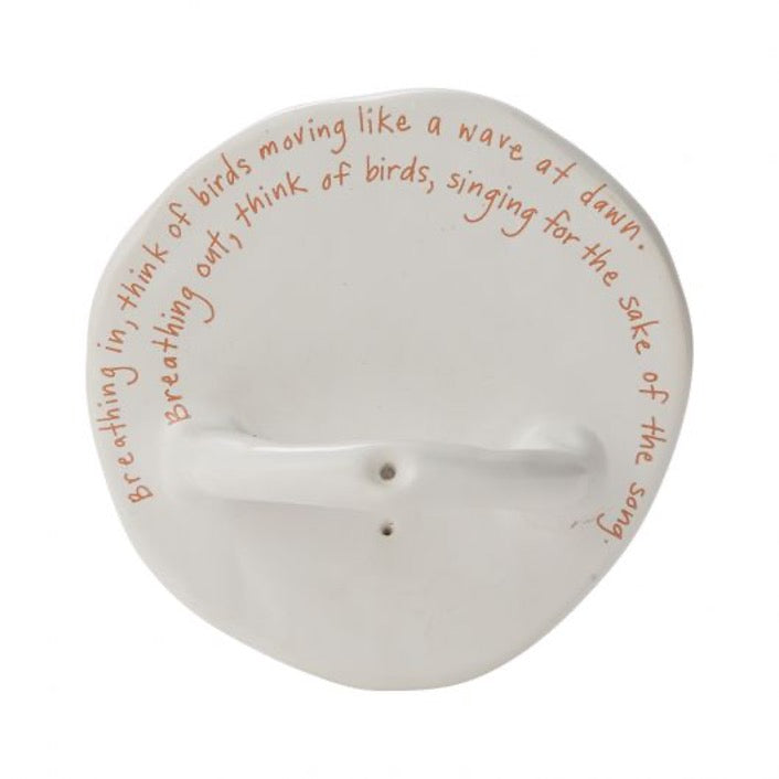 Round incense holder in white with inspirational text written around base.