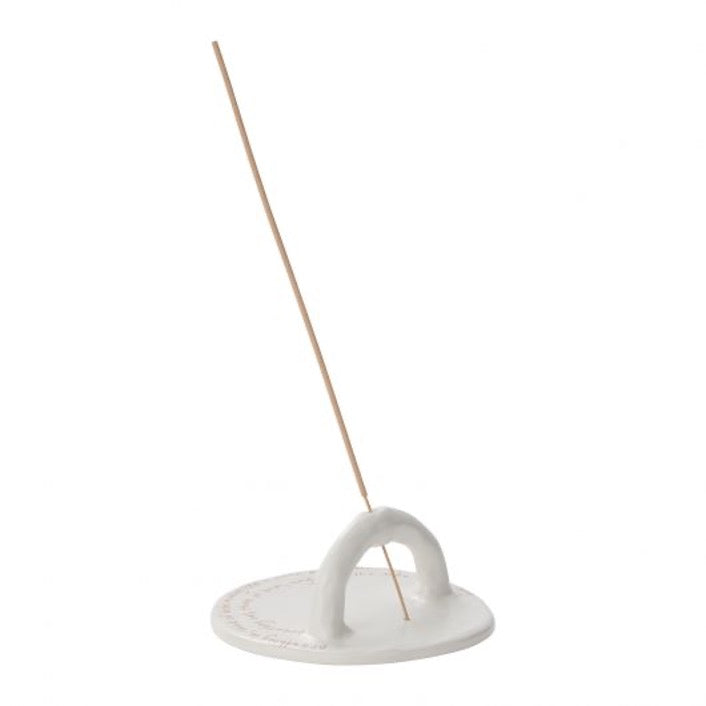 Round incense holder in white with an upright semi-arched holder with incense stick. 