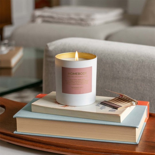 Homebody Candle, lit on a stack of books.