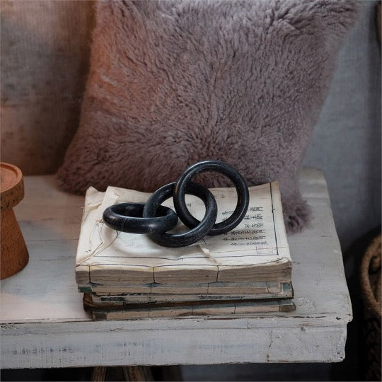 Marble chain black, 3 links on stack of old books, fur pillow on background on distressed white table