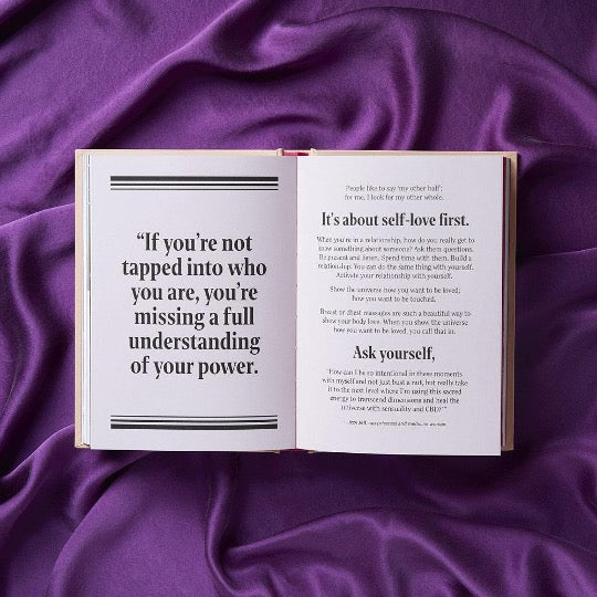 Open book with black and white text on top of purple fabric. 