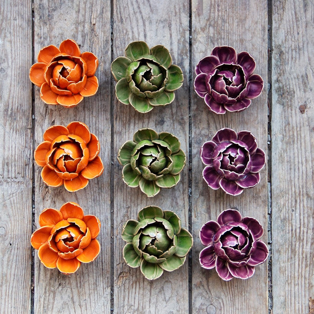 Collection of ceramic peony flowers on wooden background.