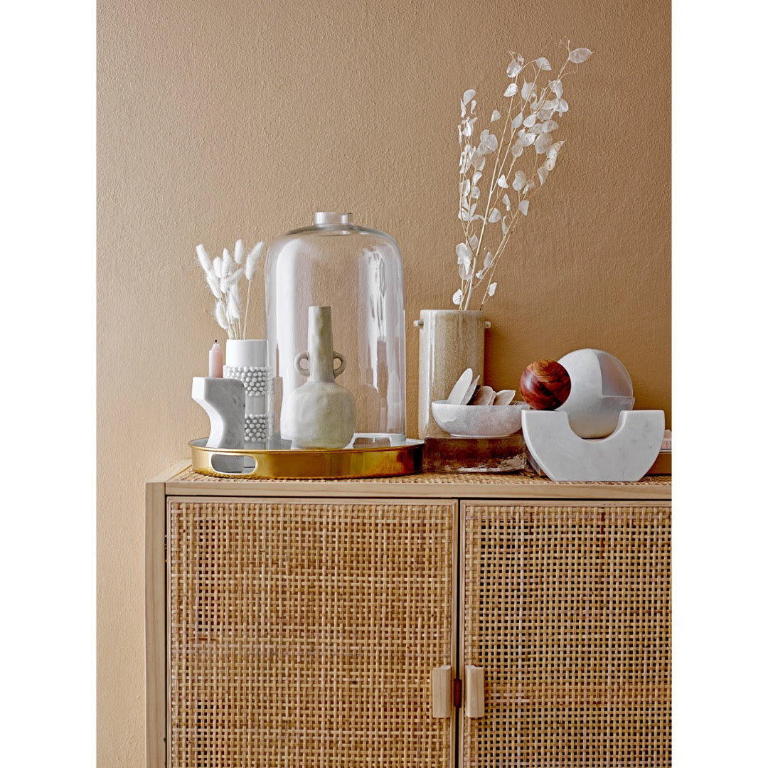 Collection of white home furnishing accessories on a cane cabinet.