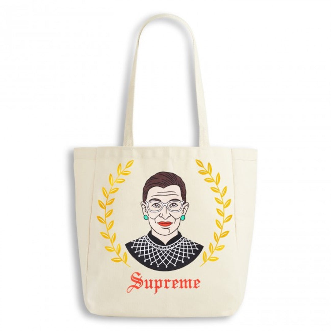 Ruth Bader Ginsburg natural tote bag with yellow leaves on either side.  Supreme text in red old english font.