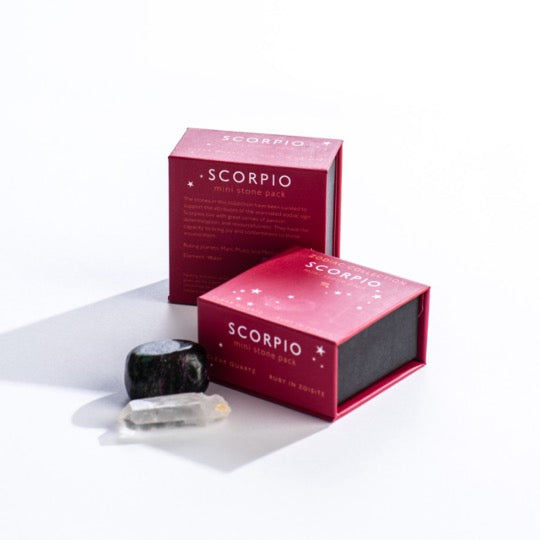 Scorpio mini stone pack text on magenta boxes with Scorpio constellation pattern. Clear quartz and polished ruby in zoisite stones in front. 