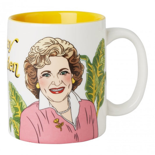 White ceramic mug with Betty White illustration, palm leaves in background with Stay Golden text in yellow. Inside mug is solid yellow.