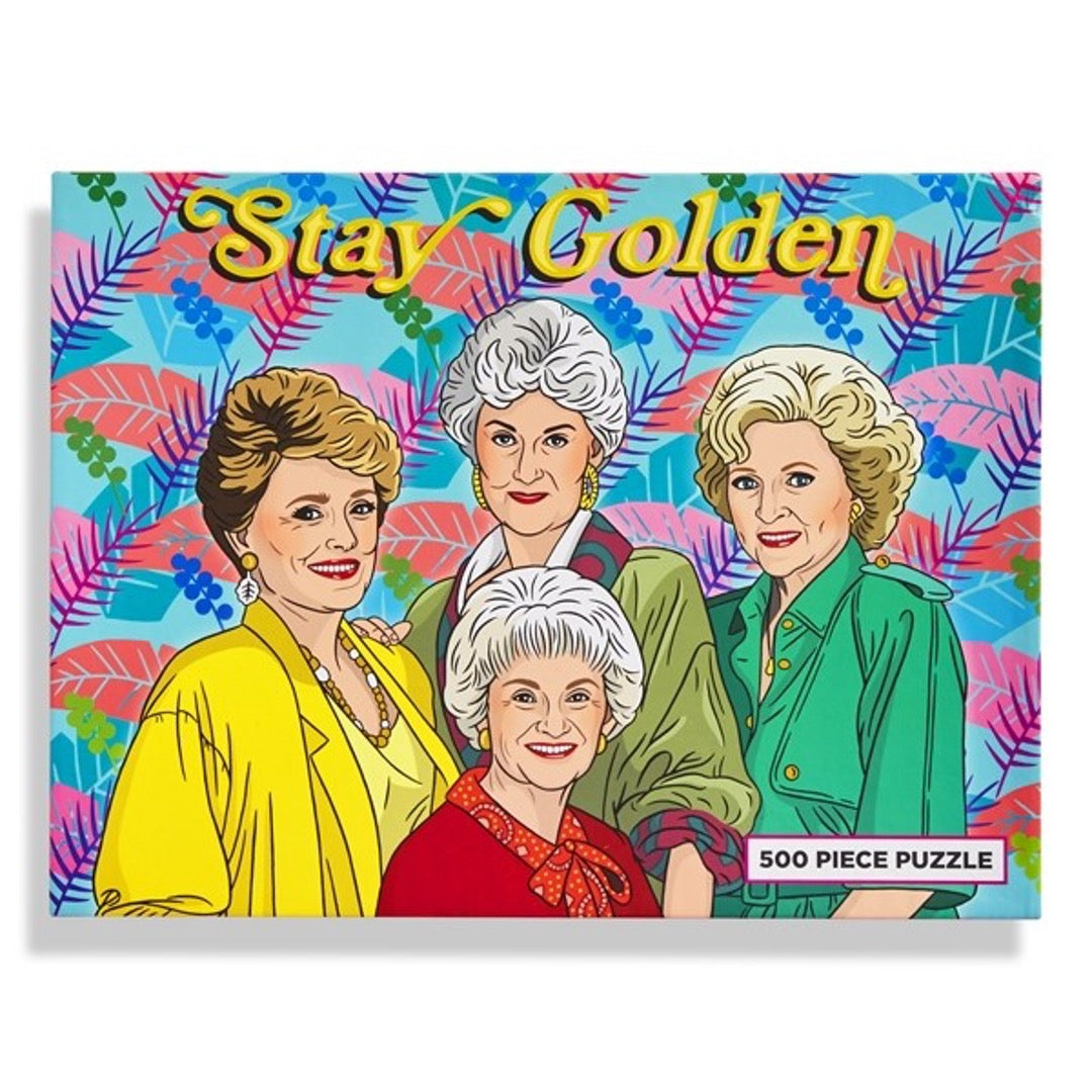 Golden Girls puzzle, multi-color palm leaves in background with Stay Golden text on top. 500 piece puzzle